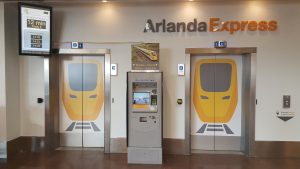 A ticket machine by a wall logo of Arlanda Express. Photo.