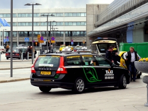 A black car with Taxi signs parked outside a building. Photo.